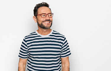 Middle age man wearing casual clothes and glasses looking away to side with smile on face, natural expression. laughing confident.