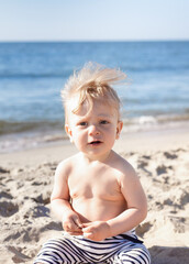 portrait of a happy, smiling boy on the beach. eight month old blond boy