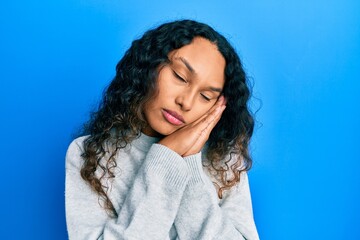Young latin woman wearing casual clothes sleeping tired dreaming and posing with hands together while smiling with closed eyes.