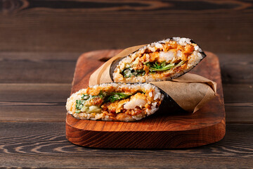  Sushi burrito , sushirrito, with shrimp rice, spice sauce, cucummber, lettuce, nori, on a wooden ...