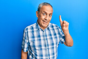 Senior hispanic man wearing casual clothes smiling with an idea or question pointing finger up with happy face, number one