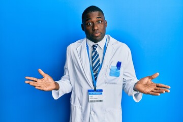 Young african american man wearing scientist uniform clueless and confused expression with arms and...