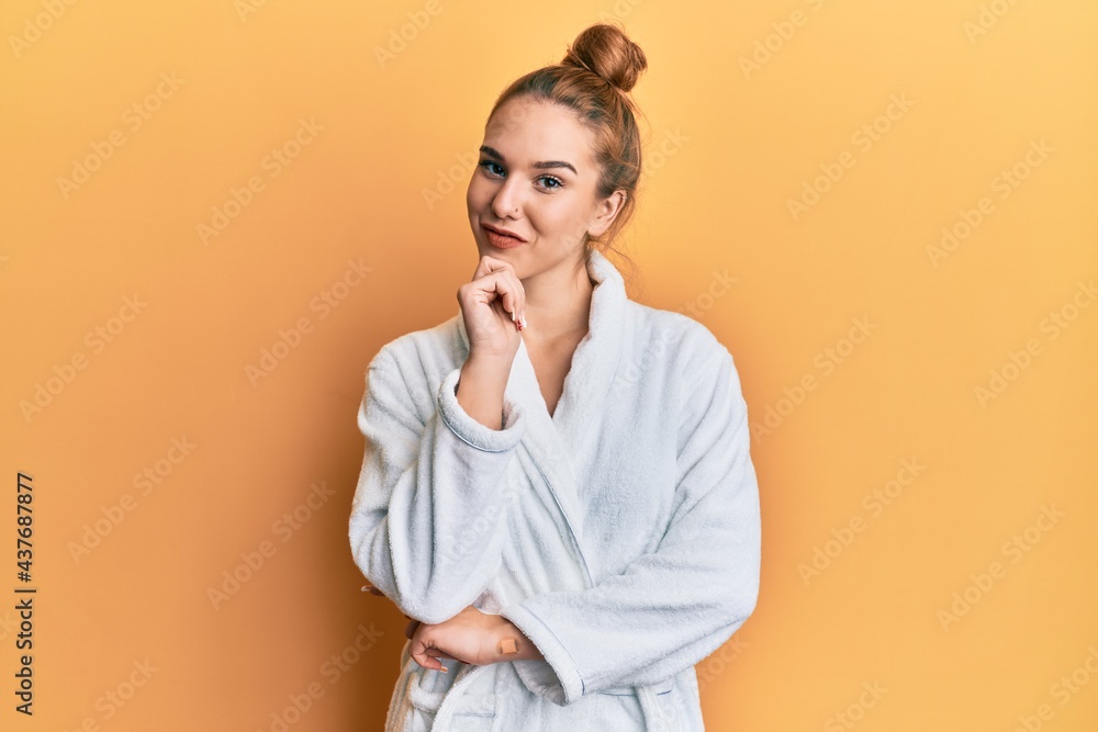 Sticker young blonde woman wearing bathrobe looking confident at the camera with smile with crossed arms and