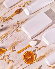 Vertical spa composition with cosmetic bottles, boxes, wooden spoons with natural ingredients, ears of rye and wheat. Beauty products mock up of cosmetics based on organic, natural cereals ingredients
