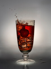 Cherry falls into glass with drink