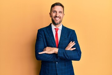 Handsome man with beard wearing business suit and tie happy face smiling with crossed arms looking at the camera. positive person.