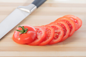 A fresh sliced tomato isolated on a wooden cutting board: Selective focus. Healthy food concept