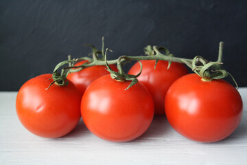 Red tomatoes on a branch on a wooden background.