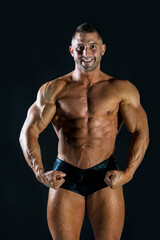 Fototapeta na wymiar Strong muscular caucasian man making bodybuilding pose on a dark background: Selective focus.