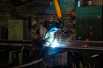 Welder at work in a factory. Industrial worker welding steel. Welding metal in the workshop with...