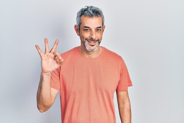 Handsome middle age man with grey hair wearing casual t shirt smiling positive doing ok sign with hand and fingers. successful expression.
