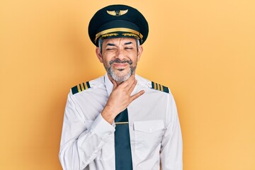 Handsome middle age man with grey hair wearing airplane pilot uniform touching painful neck, sore throat for flu, clod and infection © Krakenimages.com