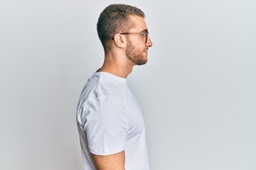 Young caucasian man wearing casual clothes and glasses looking to side, relax profile pose with natural face with confident smile.