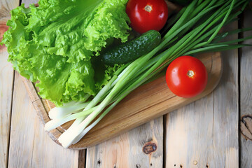 Lettuce, green onions, tomatoes, cucumbers. Set of fresh vegetables on a wooden board. Healthy diet concept.