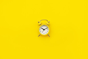 Small alarm clock. Monochrome yellow. Minimalistic concept.