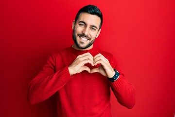 Young hispanic man wearing casual clothes smiling in love doing heart symbol shape with hands. romantic concept.