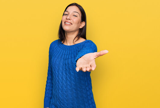 Young hispanic woman wearing casual clothes smiling cheerful offering palm hand giving assistance and acceptance.