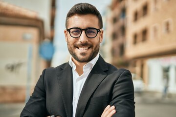 Young hispanic businessman with arms crossed smiling happy at the city.