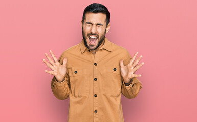 Fototapeta premium Young hispanic man wearing casual clothes celebrating mad and crazy for success with arms raised and closed eyes screaming excited. winner concept