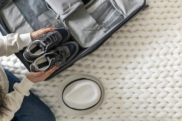 Female hands sports sneakers packing in storage container placing in suitcase for travel vacation