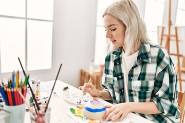 Young artist student girl smiling happy painting pottery at art studio.