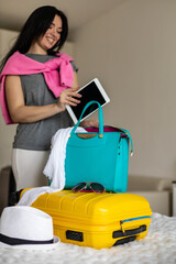 Woman hands ready travel journey putting tablet pc into handbag packing baggage at bedroom