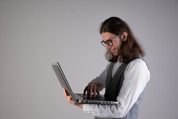 Training and new technologies, online courses, e-learning. A young man with long hair and glasses.