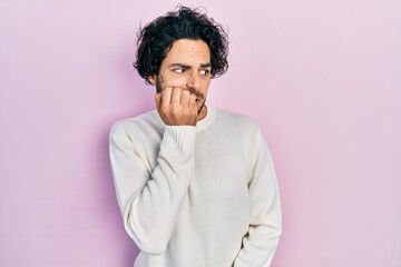 Fototapeta na wymiar Handsome hispanic man wearing casual white sweater looking stressed and nervous with hands on mouth biting nails. anxiety problem.