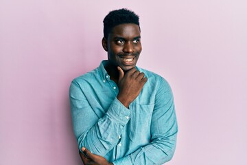 Fototapeta premium Handsome black man wearing casual clothes with hand on chin thinking about question, pensive expression. smiling with thoughtful face. doubt concept.