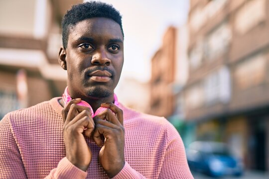 Young african american man with serious expression using headphones at the city.