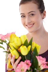 Happy young woman posing in summer dress, holding a bouquet of flowers, looking at camera, smiling. Isolated on white.