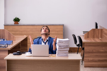 Young male employee unhappy with excessive work in the office