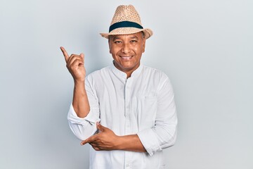 Middle age latin man wearing casual clothes and hat smiling happy pointing with hand and finger to the side