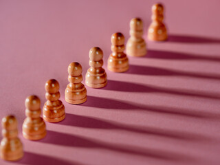 chess pieces in a row, white pawns on a pink background,