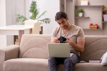 Young male freelancer holding wallet at home
