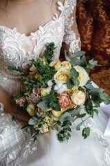 the bride in a white slinky dress holds a wedding bouquet of peonies
