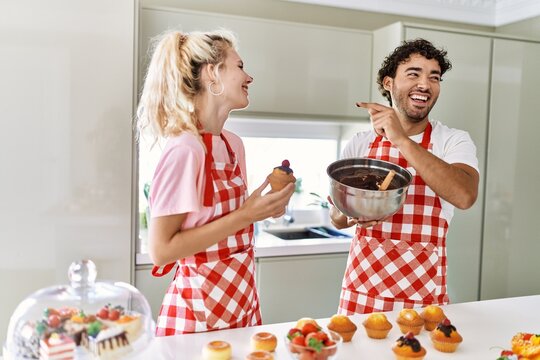 Young couple smiling happy cooking sweets at kitchen.
