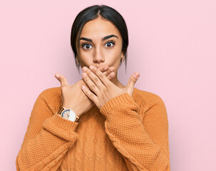 Young brunette woman wearing casual winter sweater shocked covering mouth with hands for mistake. secret concept.