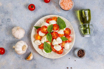 Delicious Italian caprese salad with sliced red and orange cherry tomatoes and mozzarela balls.