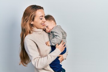 Young caucasian woman holding and hugging her son with love. Family of two bonding together. Mother holding infant toddler