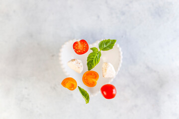 Delicious Italian caprese salad with sliced red and orange cherry tomatoes and mozzarela balls.