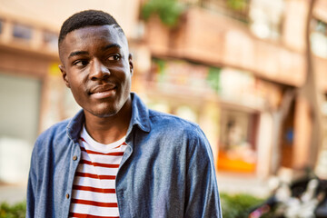 Young african american man with relaxed expression standing at the city.