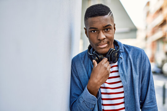 Young african american man with serious expression using headphones at the city.