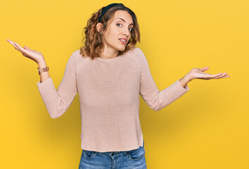 Beautiful young caucasian woman wearing casual sweater clueless and confused expression with arms...