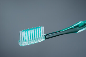 Green toothbrush on a gray background. Toothbrush isolate.