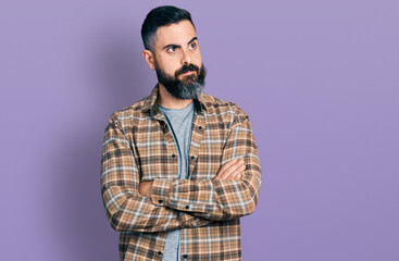 Hispanic man with beard with arms crossed gesture smiling looking to the side and staring away thinking.