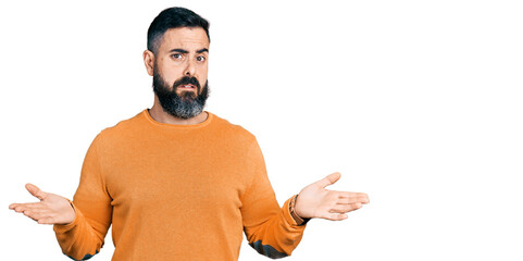 Hispanic man with beard wearing casual winter sweater clueless and confused with open arms, no idea...