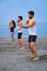 group of people exercising at the beach with kettle bells