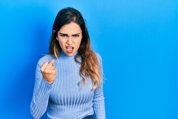 Fototapeta premium Young hispanic girl wearing casual clothes angry and mad raising fist frustrated and furious while shouting with anger. rage and aggressive concept.