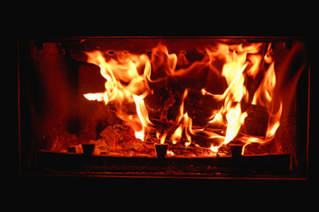 Fire in the fireplace with glass close-up. Firewood is burning in the fireplace.